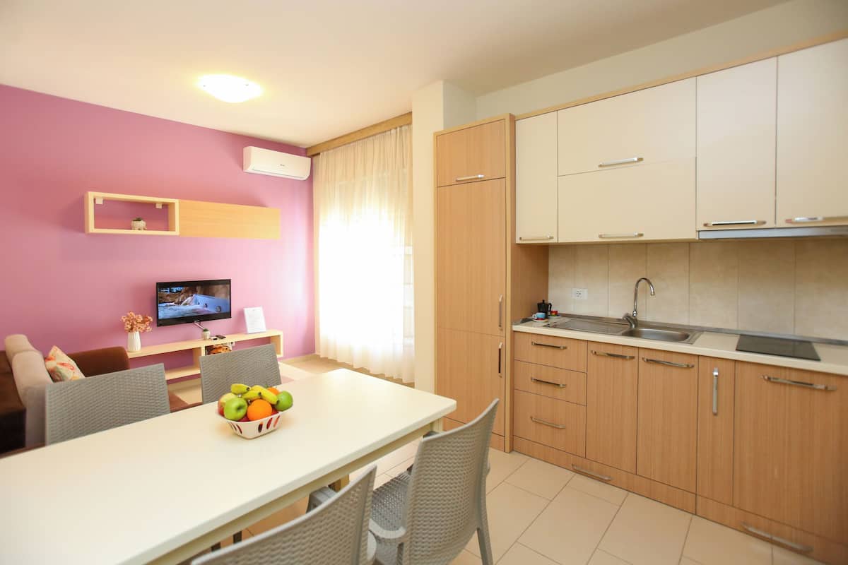 Une cuisine moderne avec des meubles en bois, un plan de travail blanc et un coin repas avec une table dressée pour deux personnes.