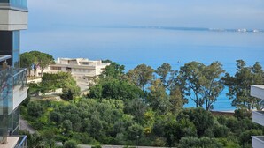 Vista costera con un edificio moderno, abundante vegetación y un mar azul cristalino.