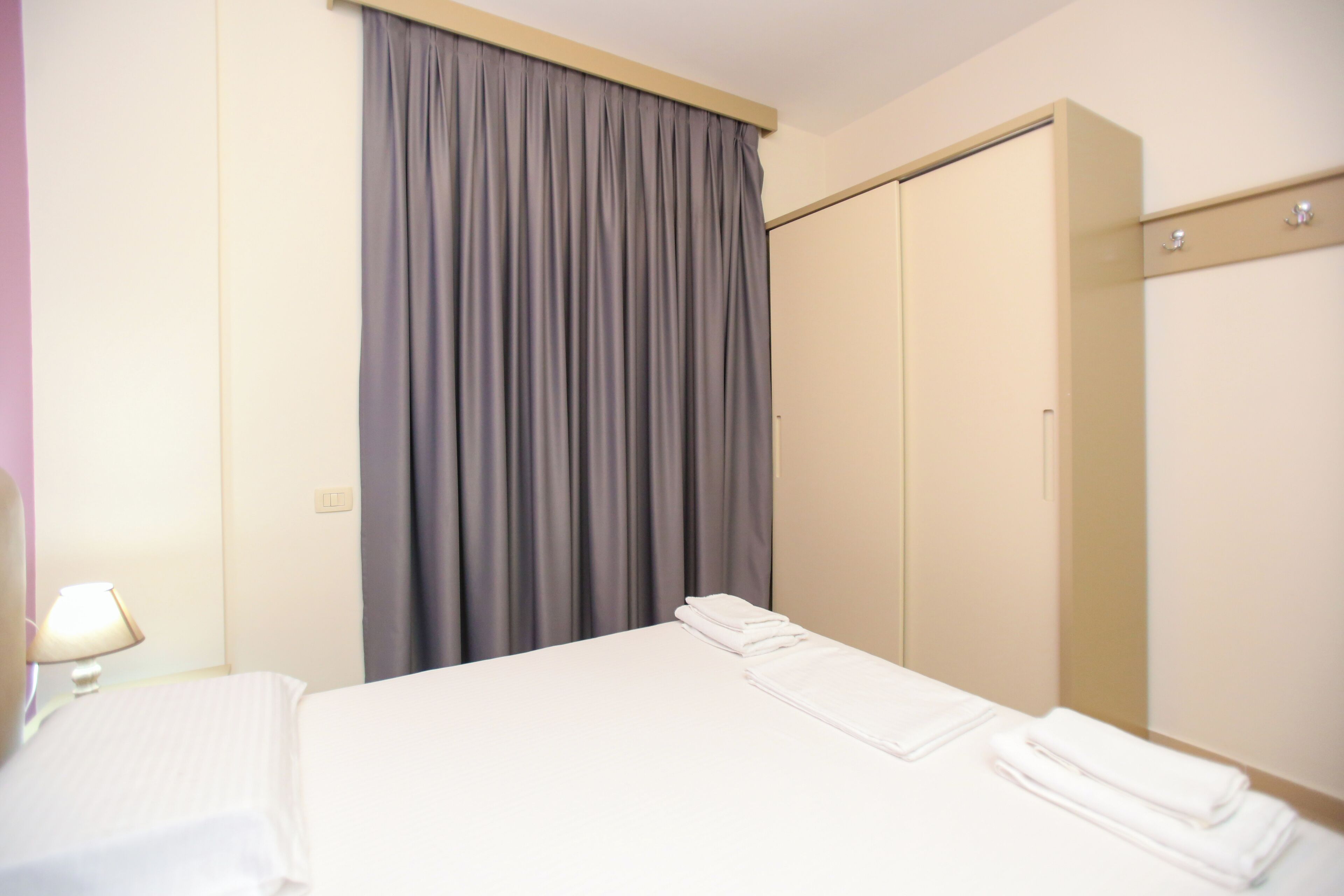 Ein Hotelzimmer mit Bett, Kleiderschrank und Vorhang.