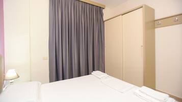 Ein Hotelzimmer mit Bett, Kleiderschrank und Vorhang.