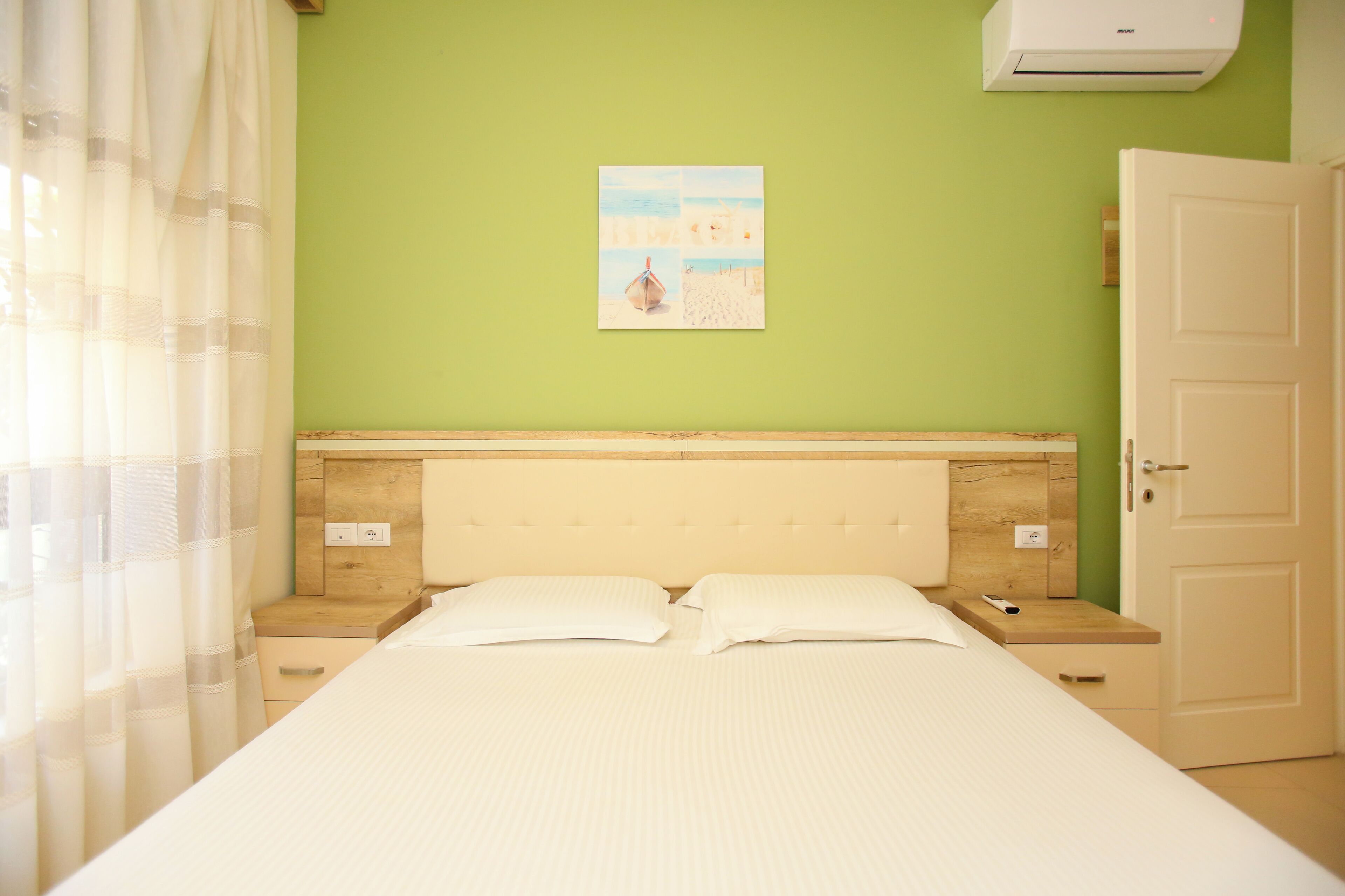 Un dormitorio con cama, mesita de noche, aire acondicionado y una puerta.