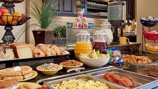 Un bufé con diversas opciones de desayuno, incluyendo bollería, frutas y bebidas.
