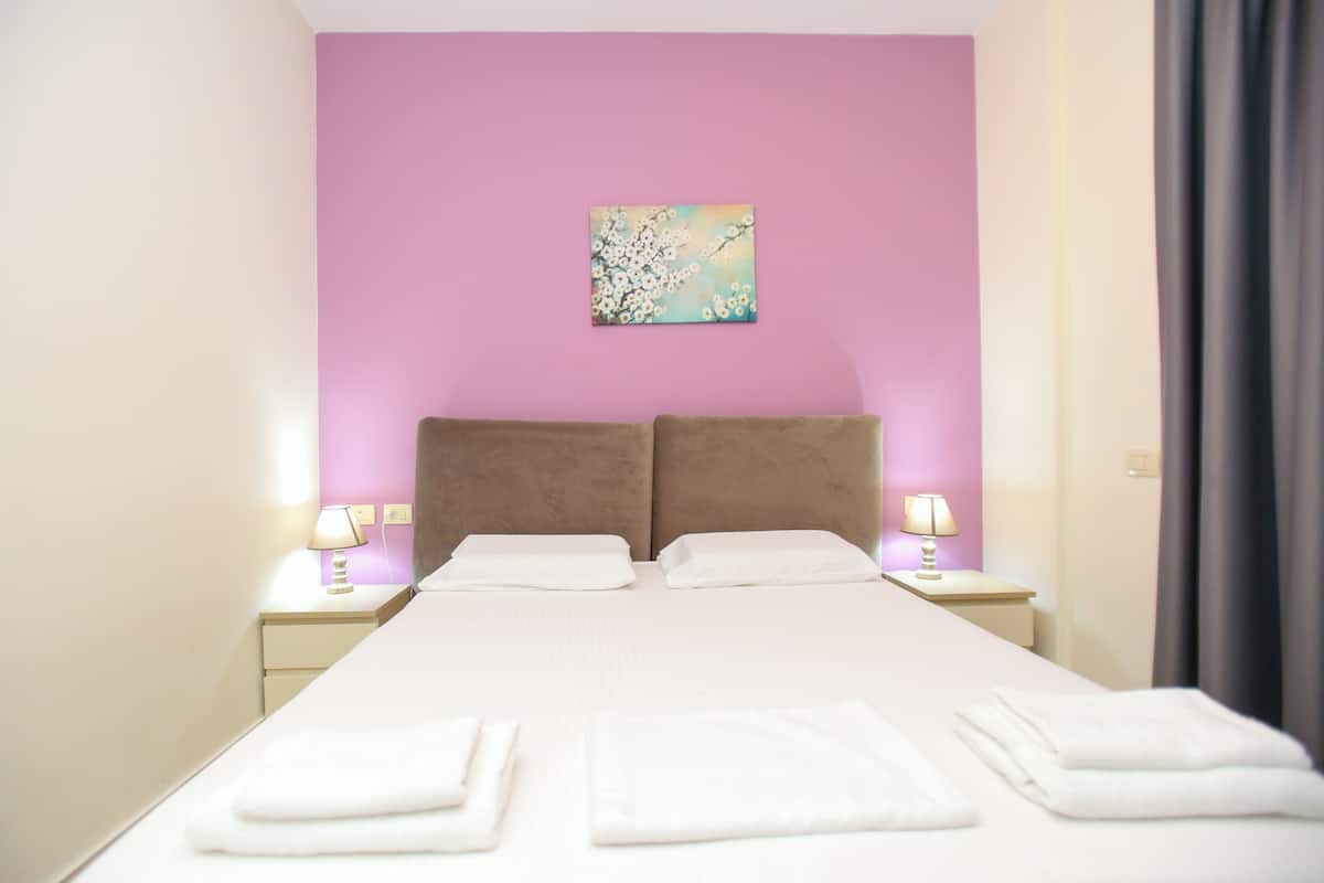 Une chambre d’hôtel avec un grand lit, deux oreillers, une table de chevet avec une lampe et un tableau au mur.