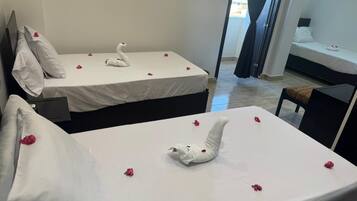 Quarto de hotel com duas camas, cada uma decorada com um toalha em formato de cisne e pétalas de rosa espalhadas.
