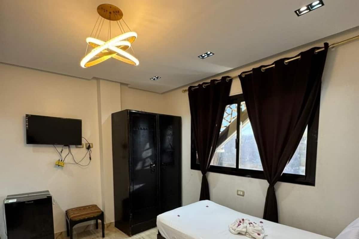 Un dormitorio con cama, televisión, armario, escritorio y alfombra.