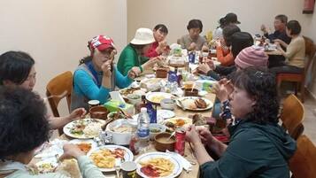 Un grupo de personas sentadas alrededor de una mesa con diferentes platos, sugiriendo un ambiente de comida compartida.