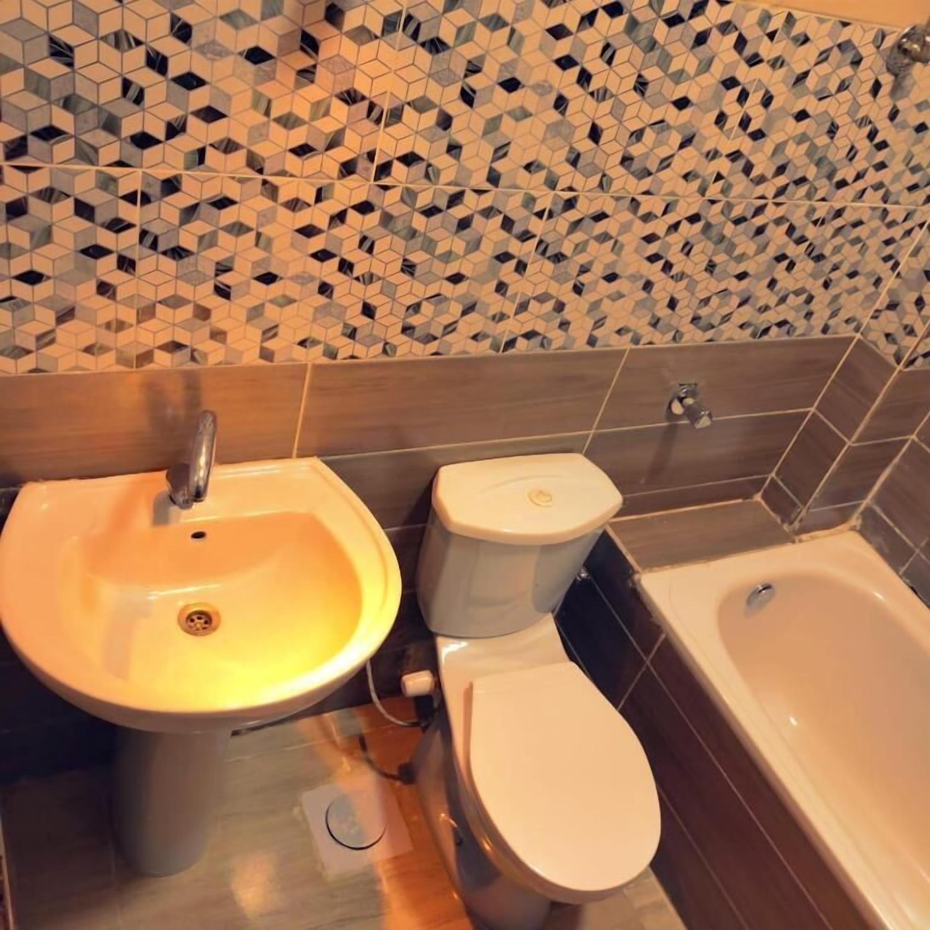 Un baño con lavamanos, inodoro y bañera.