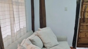 Un sofá beige con varios cojines en una habitación con suelo de baldosas y una puerta de madera.
