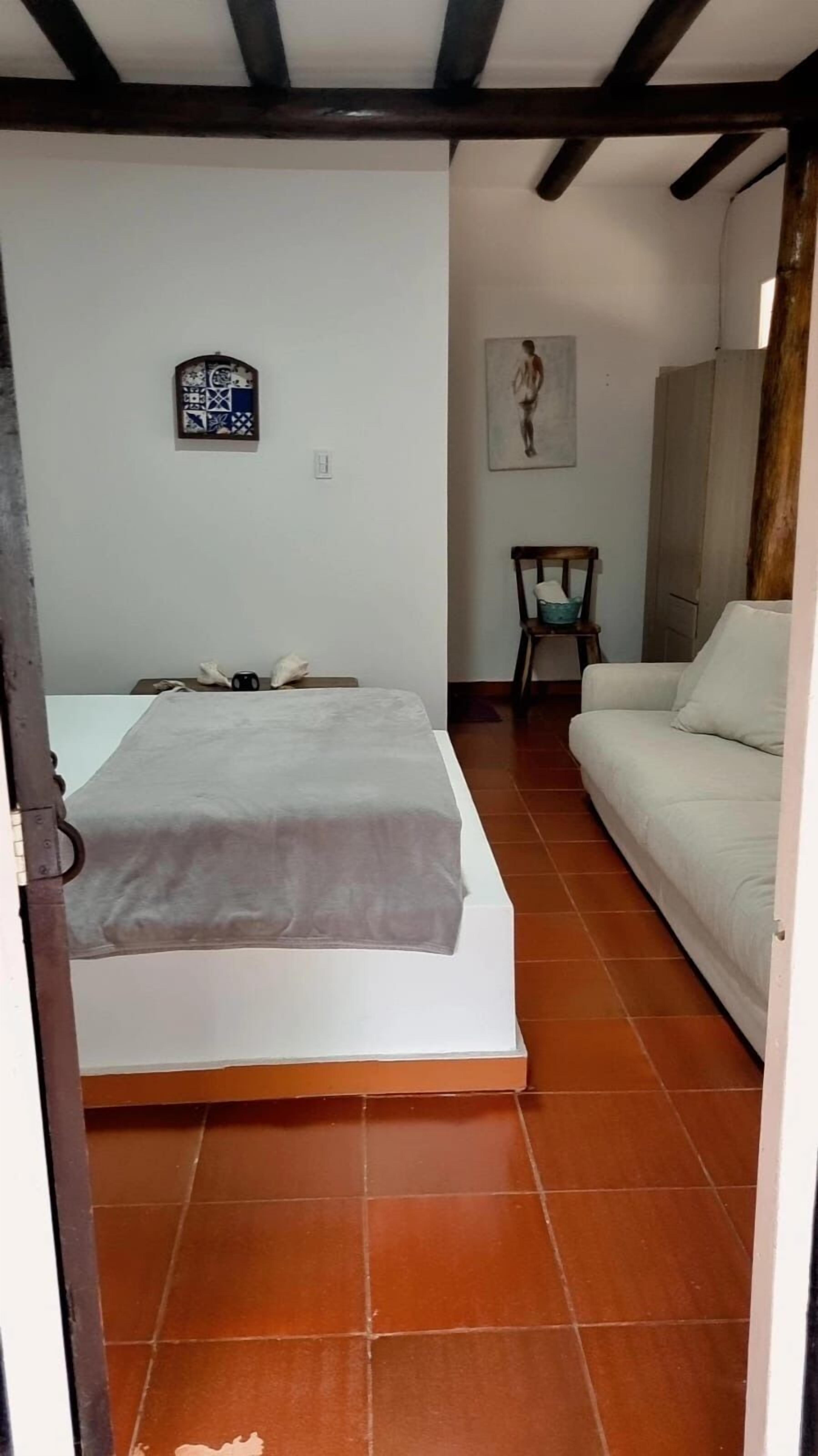A bedroom with a bed, a chair, and a sofa.