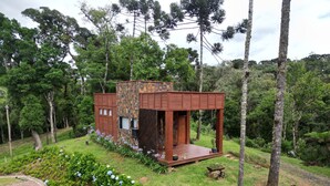 Une cabane moderne avec une façade en pierre, une terrasse en bois et un petit porche.