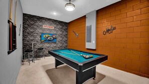 A pool table with billiard balls, a guitar, and a 'MUSIC' sign on a brick wall.