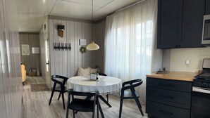 Uma cozinha moderna com uma mesa de jantar redonda, cadeiras pretas e bancada preta com micro-ondas.