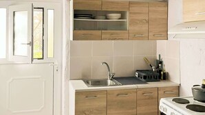 A compact kitchen with wooden cabinets, a stainless steel sink, and a stove.