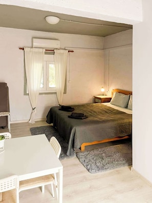 A small, single-bed room with a desk, chair, and a window with curtains.