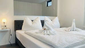 Une chambre d’hôtel avec un lit bien fait, une lampe de chevet et un miroir au-dessus du lit.