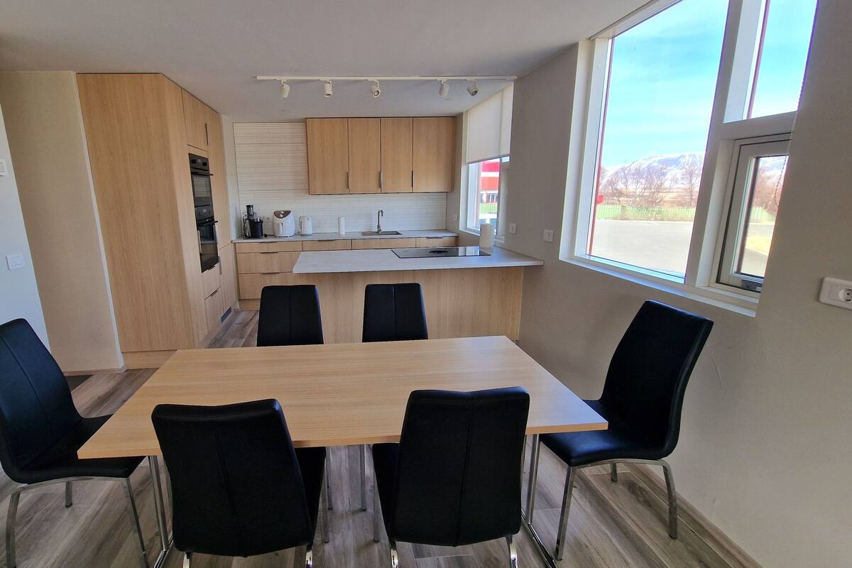 A compact kitchen with wooden cabinets, a central island, and a dining area with a table and chairs.