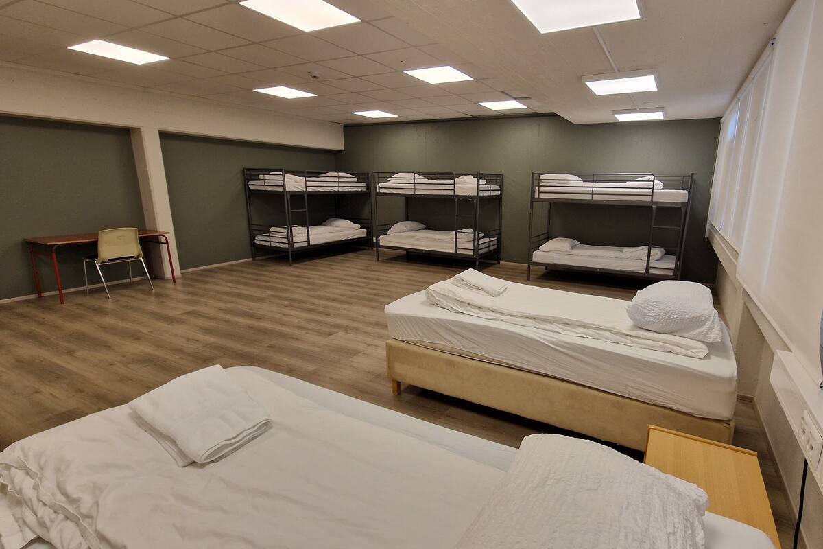 A hotel room with bunk beds, a single bed, a desk, and a chair.