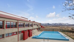 A building with a swimming pool and hot tub, surrounded by mountains. - Hunavellir Guesthouse (Blönduós)