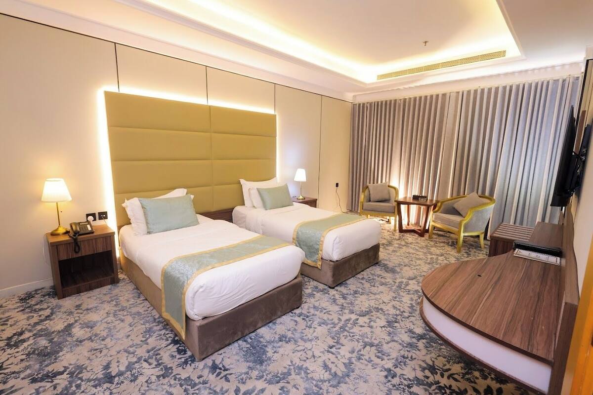 Une chambre d’hôtel avec deux lits, une télévision, un bureau et une chaise.