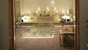 A formal event space with a stage, white floral arrangements, and a reflective floor. - diamond vision hotel (Jeddah)