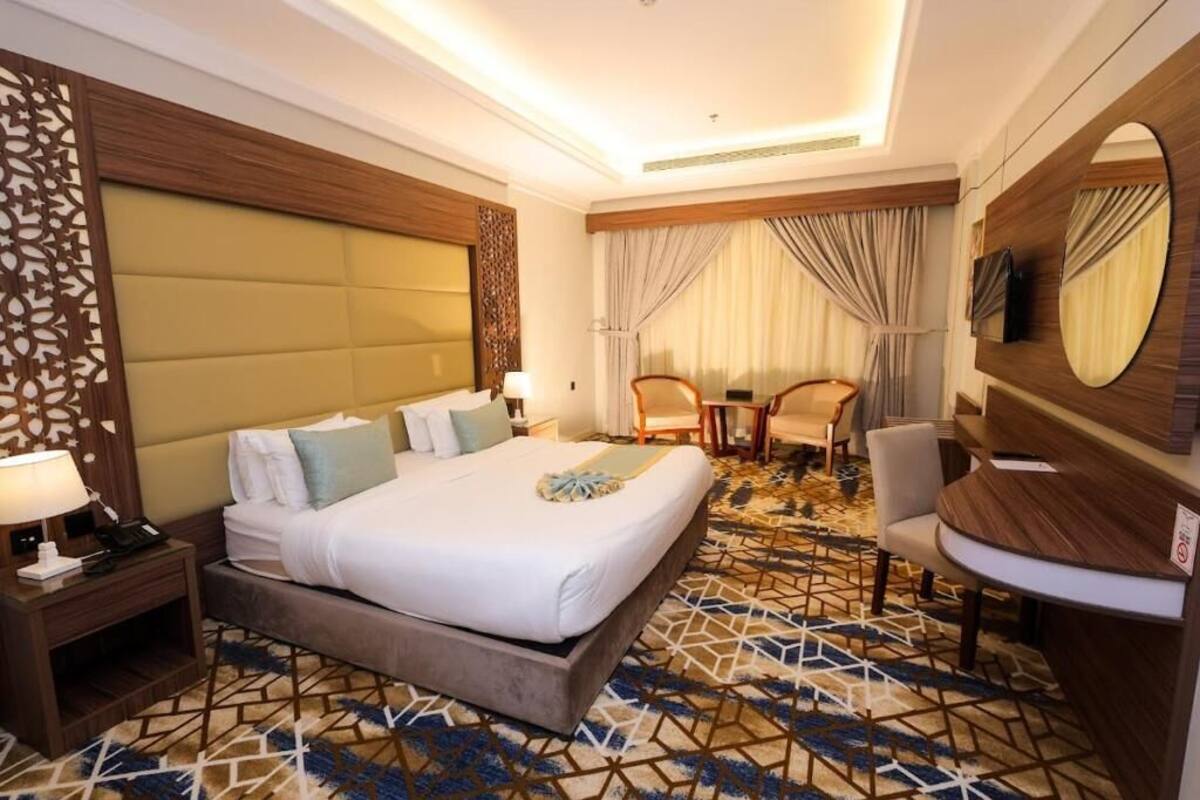 Une chambre d’hôtel avec un grand lit, un bureau, une chaise, une télévision et un panneau décoratif au mur.