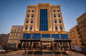 A multi-story hotel with a central entrance, a visible signboard, and a well-lit facade.