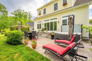 A patio with outdoor furniture, a hot tub, and a stone wall. - In-Home Arcade | Hot Tub | Golf | Close to Beach (Old Orchard Beach)