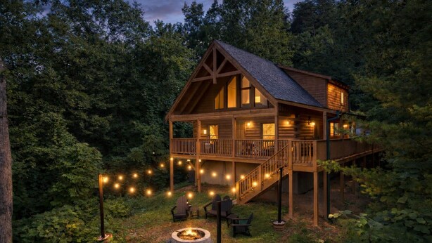 A wooden cabin with a balcony, surrounded by trees.