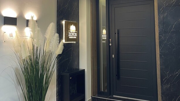 A modern entrance with a dark door, a reception desk, and a potted plant. - Superior Suite | Zotos Luxury Living #2 (Thessaloniki)
