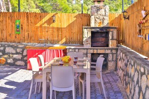 Enjoy al fresco dining in this patio with a barbecue area, table, and wicker chairs.