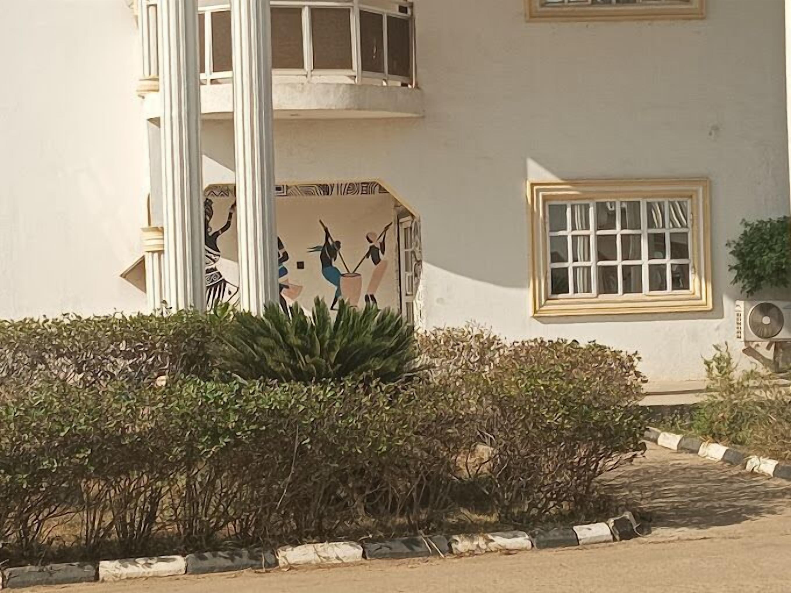 Un bâtiment à la façade blanche, une fenêtre avec un cadre blanc et une colonne ornée d’un motif décoratif.