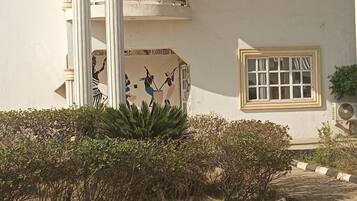 Un bâtiment à la façade blanche, une fenêtre avec un cadre blanc et une colonne ornée d’un motif décoratif.