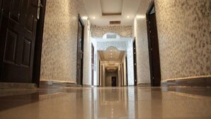 Un pasillo con piso pulido, paredes con diseño y un arco central que da a una puerta oscura.