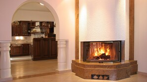 Een moderne keuken met een open haard, houten kastjes en een betegelde vloer.