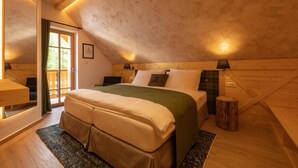 A cozy bedroom with a large bed, wooden walls, and a sloped ceiling.