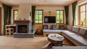 Ein gemütliches Wohnzimmer mit Kamin aus Stein, einem großen Ecksofa und einem flachbildfernseher, der darüber angebracht ist.