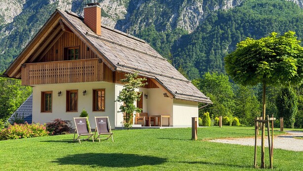 A chalet with a sloped roof, wooden exterior, and a well-maintained lawn.