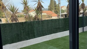 A view from a balcony with artificial grass, a green hedge, and a row of palm trees. - Comfortable gîte ideally located (Saint-Martin-d'Ardèche)