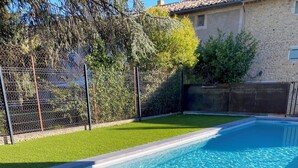 A rectangular swimming pool with a tiled edge, surrounded by a well-maintained lawn and a chain-link fence. - Comfortable gîte ideally located (Saint-Martin-d'Ardèche)