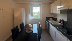 A compact kitchen with a dining area, a window with a view, and a refrigerator. - Air-conditioned accommodation downtown Rodez  (Rodez)