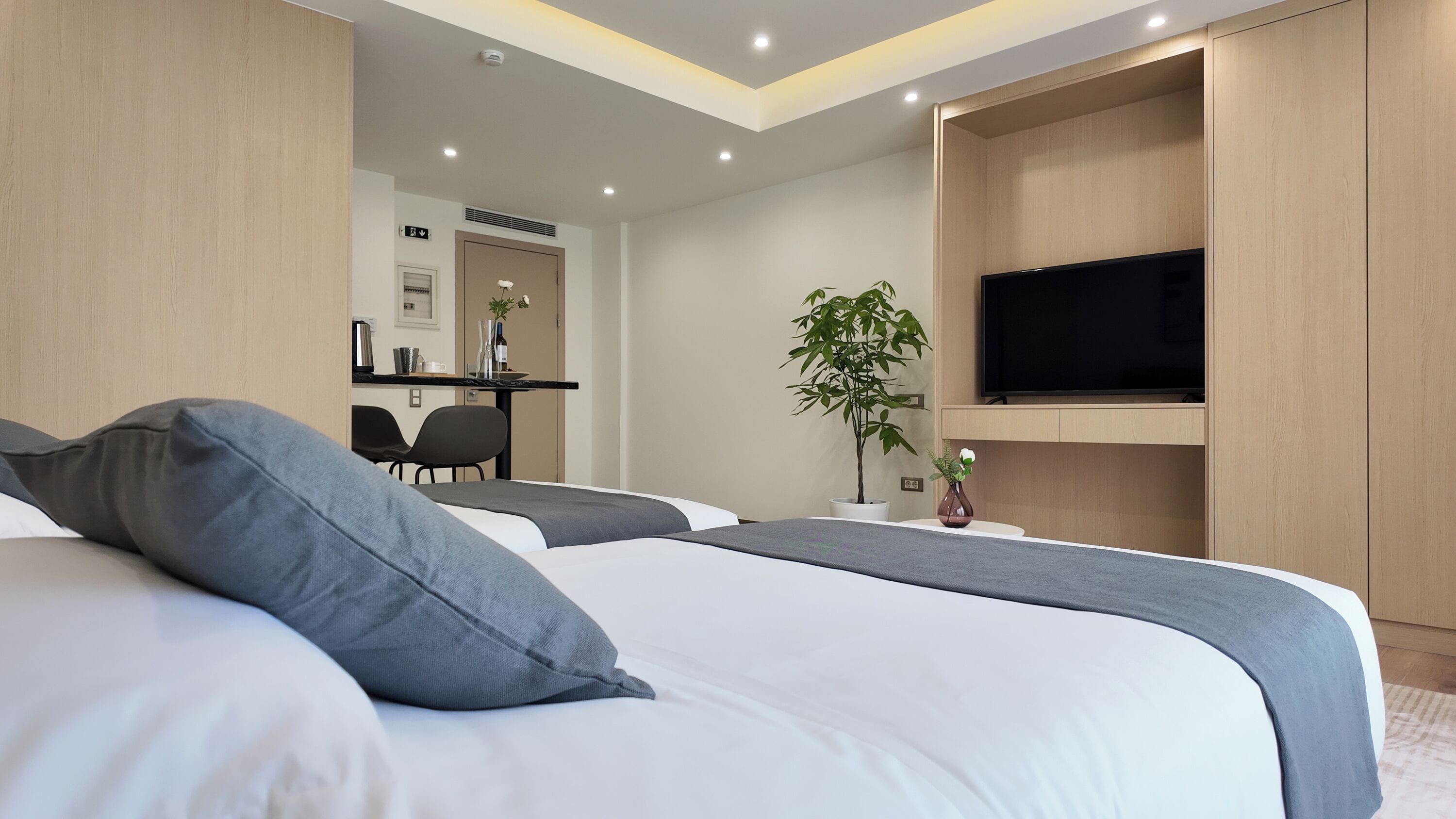 A modern hotel room with a large bed, a desk, and a TV.