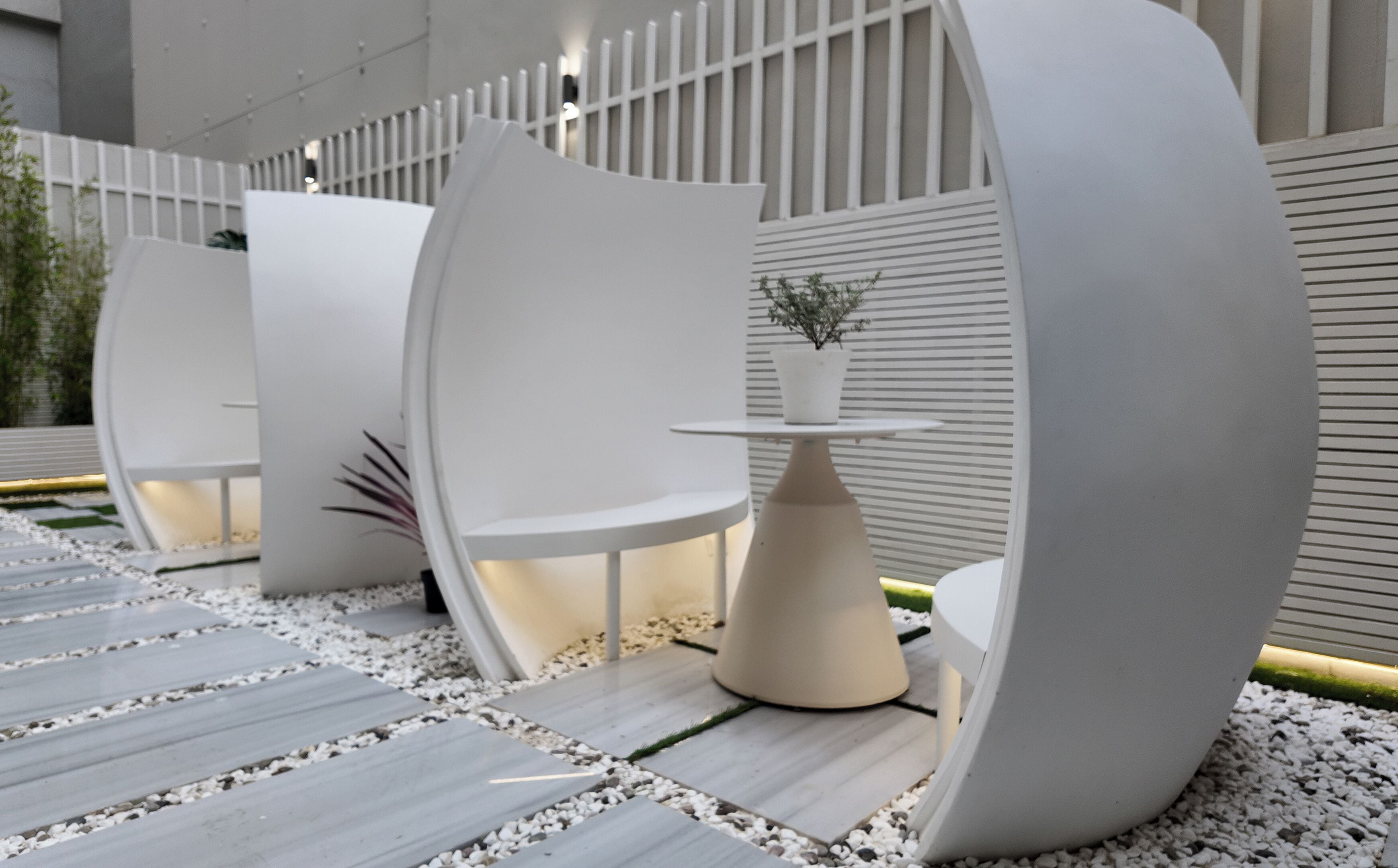A modern outdoor seating area with white curved structures and a central table.