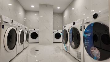 A modern laundry facility with multiple washing machines, marble flooring, and recessed ceiling lights.