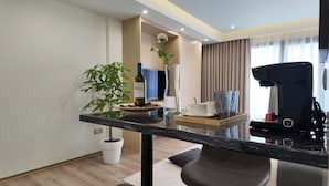 Camera d'albergo moderna con un piano di lavoro in marmo, una pianta in vaso, una bottiglia di vino e una macchina da caffè.