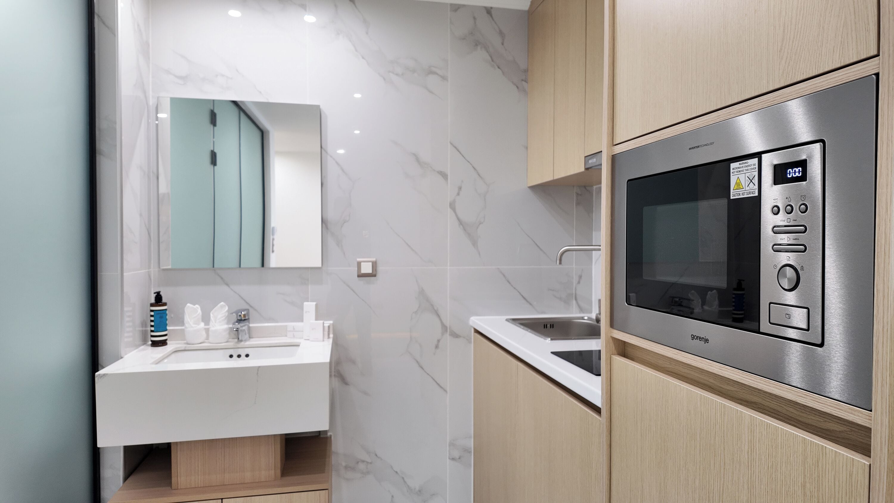 A modern bathroom with a white sink, mirror, and a built-in oven.
