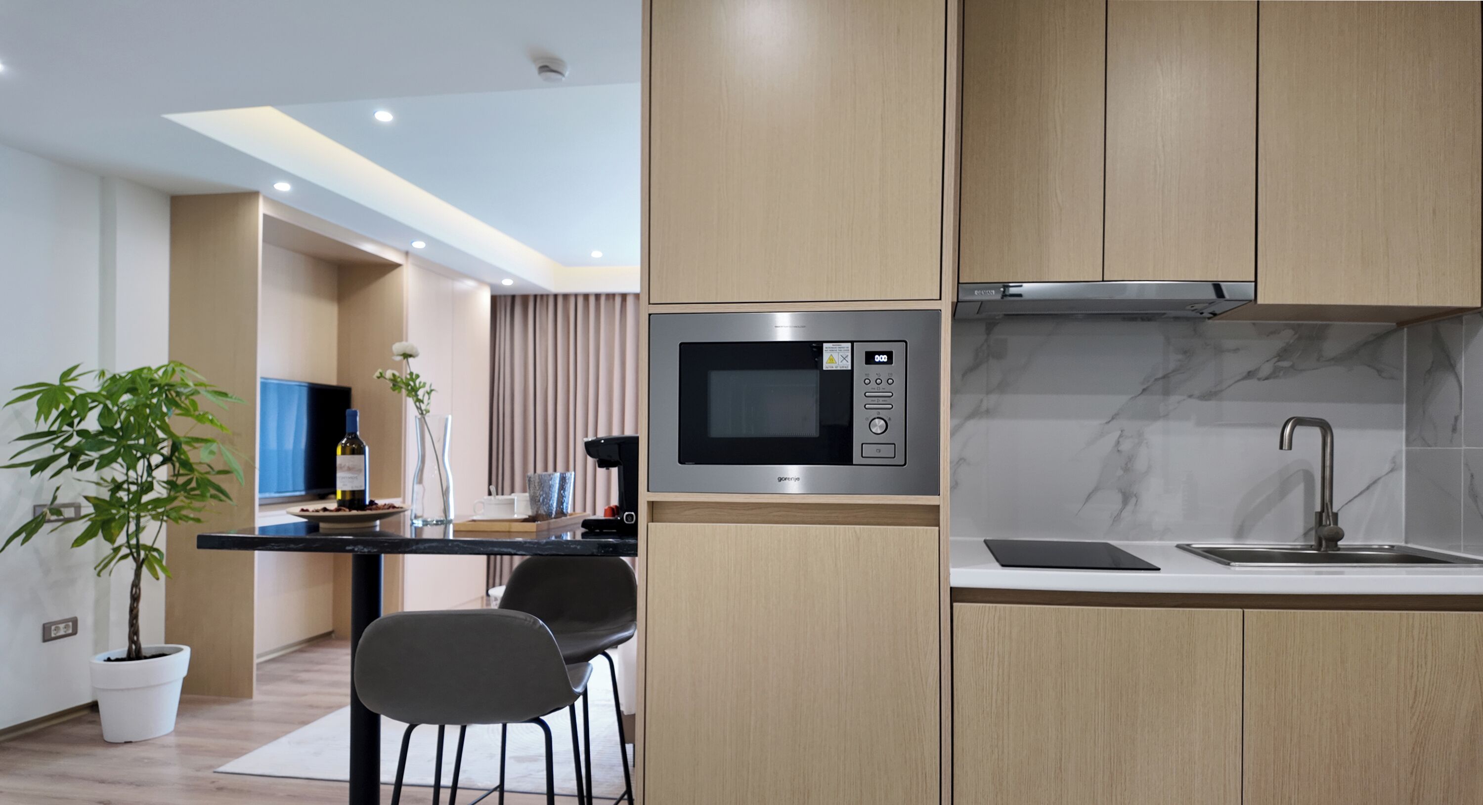 A modern kitchen with a built-in microwave, a stainless steel sink, and wooden cabinets.