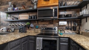 A kitchen with granite countertops, stainless steel appliances, and wooden shelves. - 
Pool, Game Room + Office - Near the Frisco Star (Frisco)