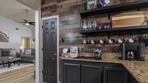 A modern kitchen with dark cabinetry, a granite countertop, and a coffee station. - 
Pool, Game Room + Office - Near the Frisco Star (Frisco)