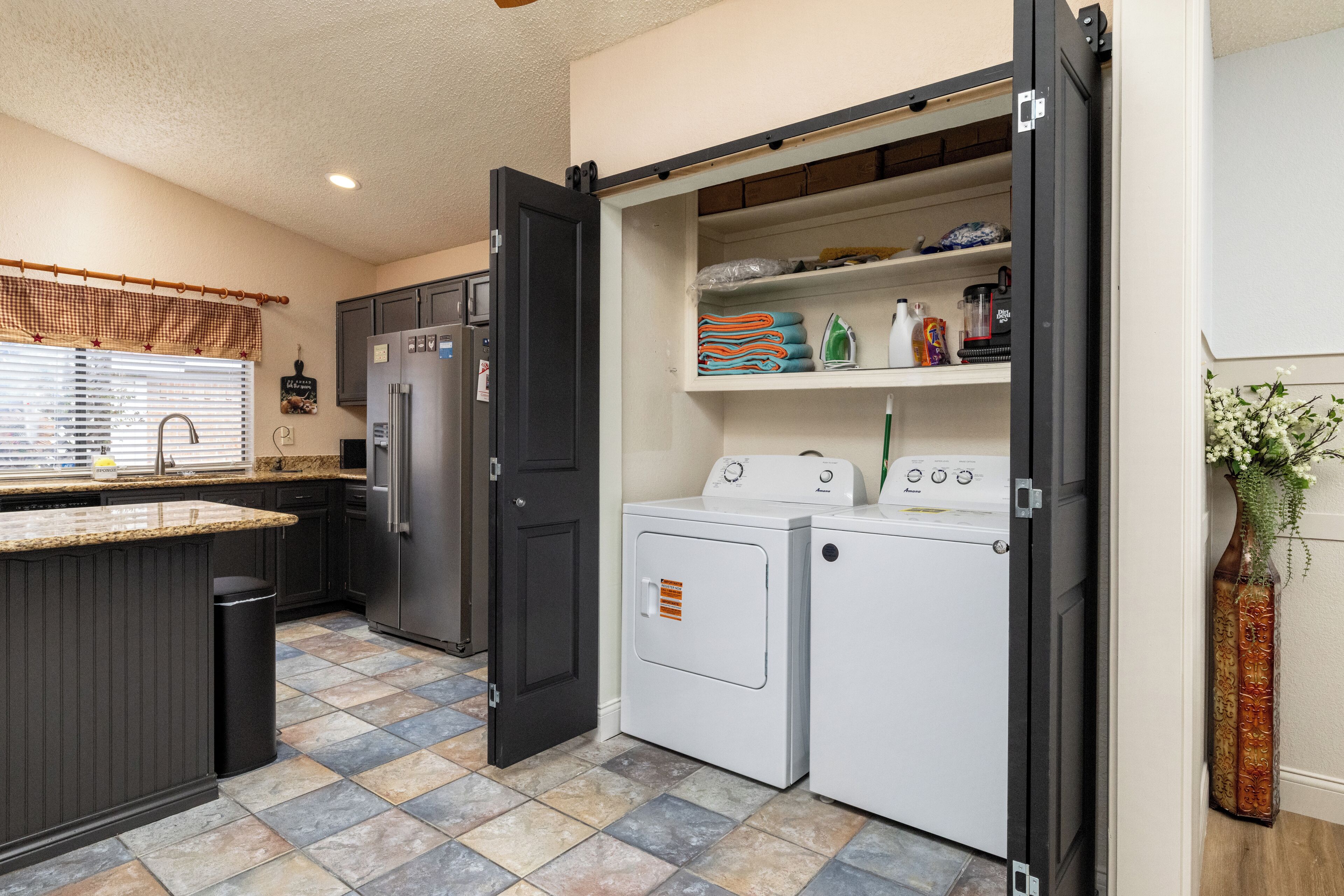 A compact kitchen with a central island, a built-in washer and dryer, and a pantry with shelves.