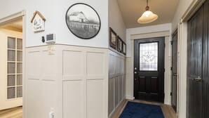 A hallway with a black door, a blue rug, and a wall-mounted picture of a barn. - 
Pool, Game Room + Office - Near the Frisco Star (Frisco)